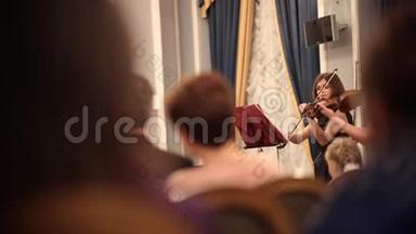 室内乐团。 在演出中拉小提琴的年轻女子。 看演出的人
